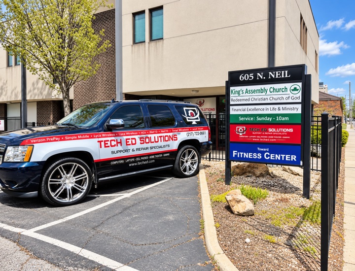 The TechEd and Solutions vehicle parked outside 605 North Neil Street in Champaign, beside the building directory sign listing Tech Ed Solutions